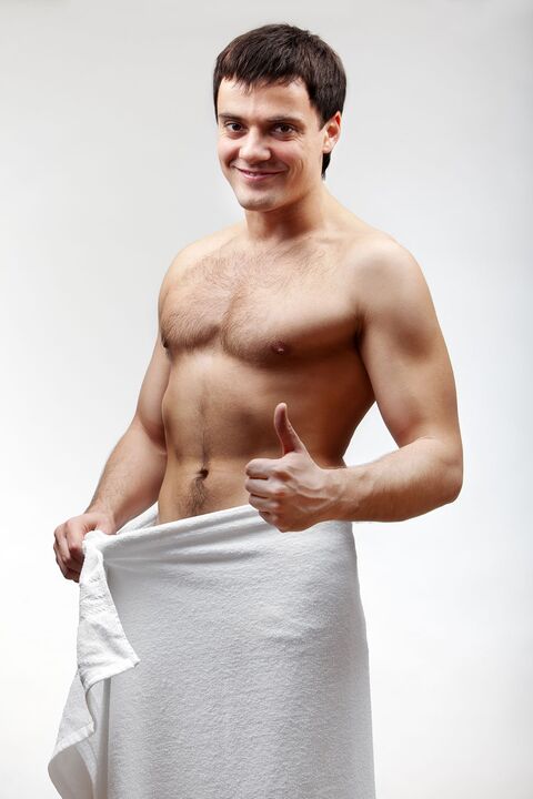 Man in towel is satisfied with the enlargement of his penis